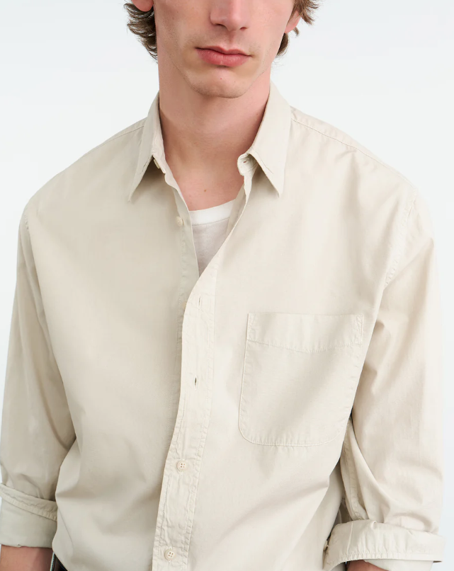 Man wearing a beige button-up shirt on a white background
