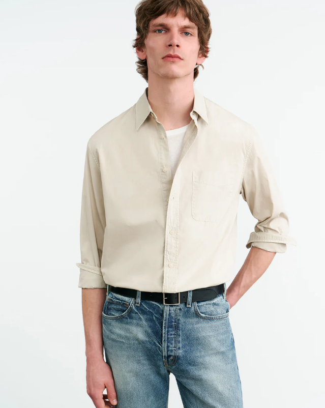 Man wearing a beige shirt and blue jeans on a white background