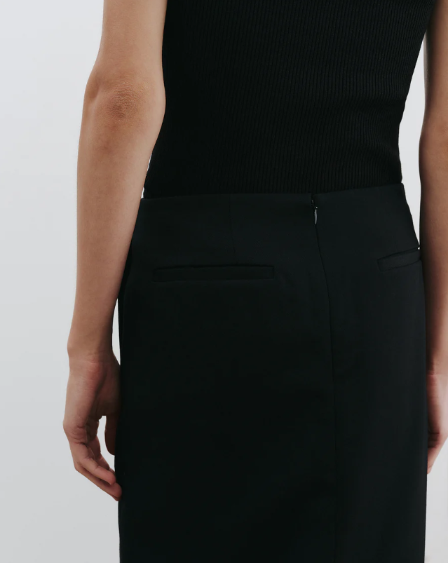 Person wearing a black sleeveless top and black pants on a white background