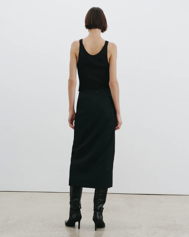 Person wearing a black sleeveless top and skirt set against a white background