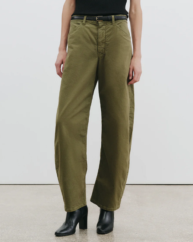 Person wearing olive green pants and black boots on a white background