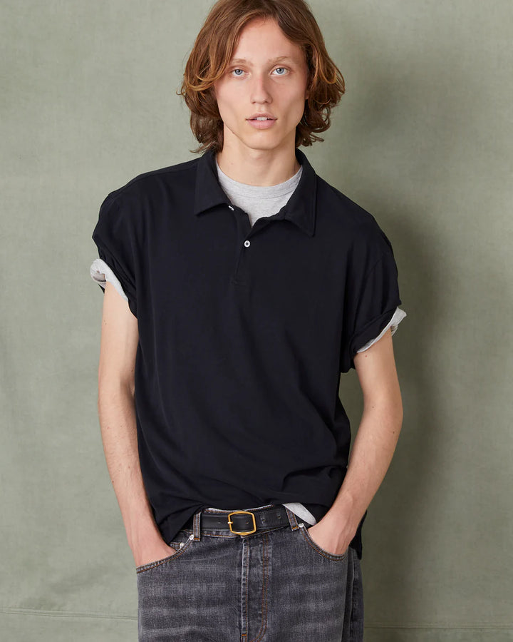 Person wearing a black polo shirt with white trim against a green background