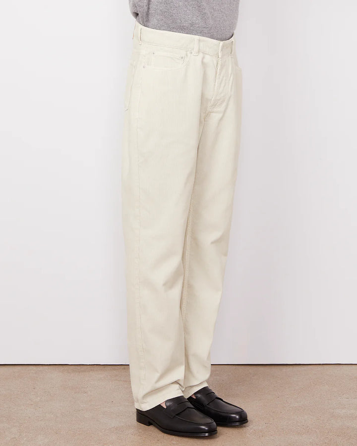 Person wearing beige pants and black shoes on a plain background