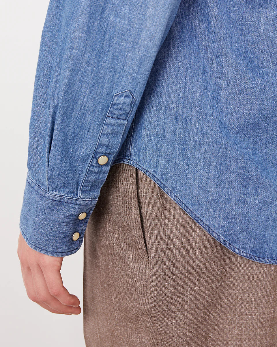 Close-up of a person wearing a blue denim shirt over a brown garment on a white background
