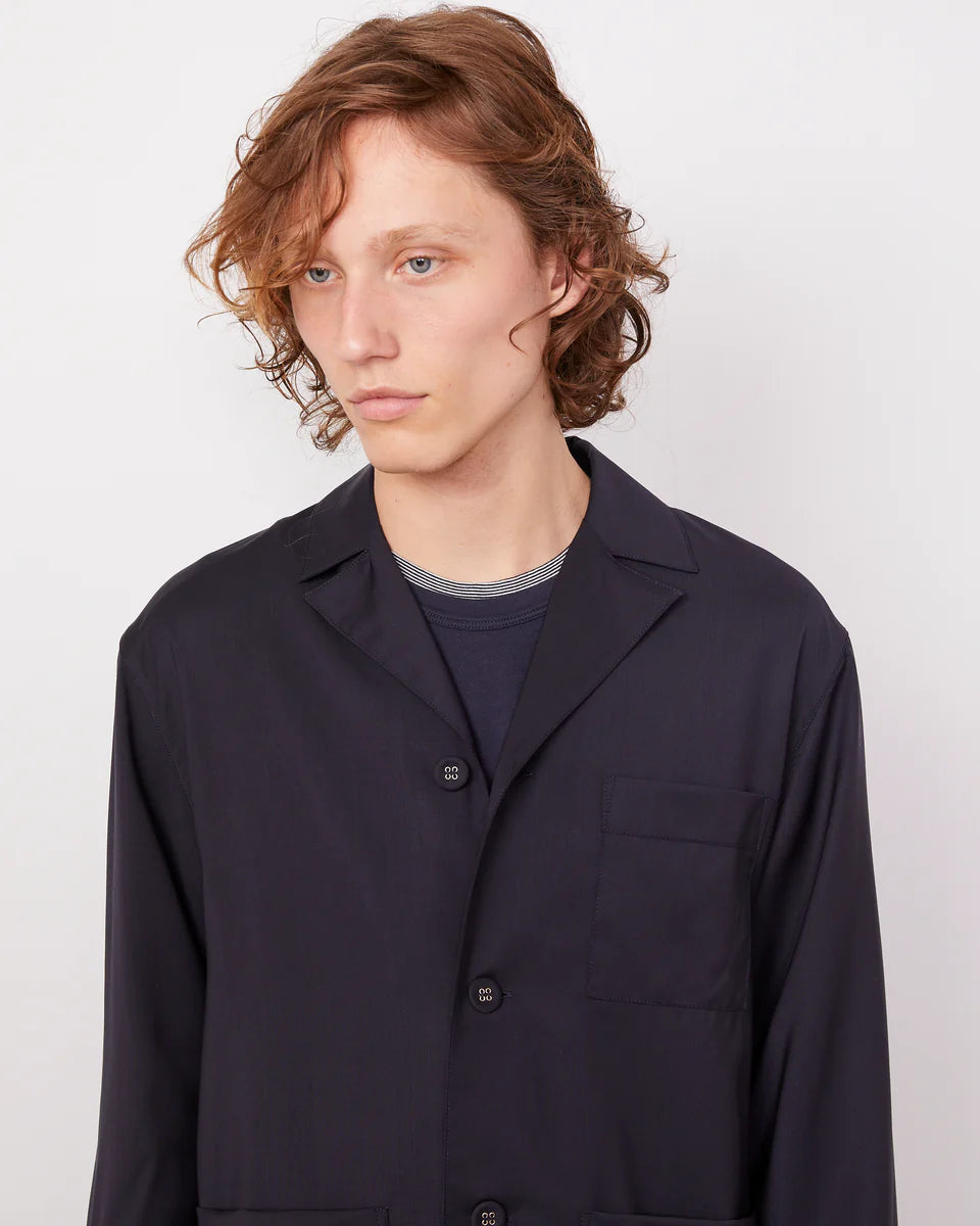 Person wearing a dark blue coat against a plain background