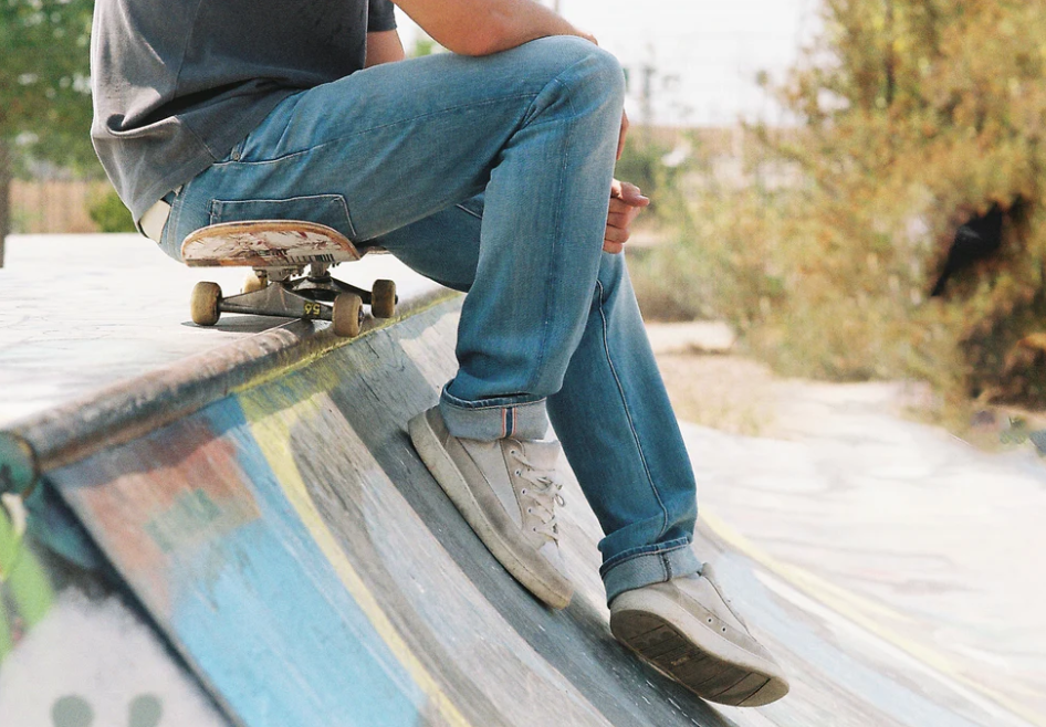 Person sitting on a skateboard at a skate park with blurred background