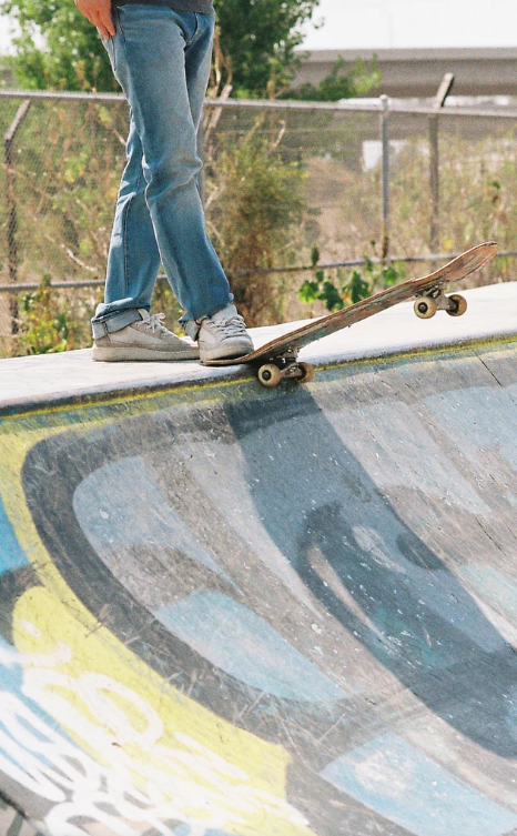 Person skateboarding on a concrete ledge with a graffiti-covered wall in the background
