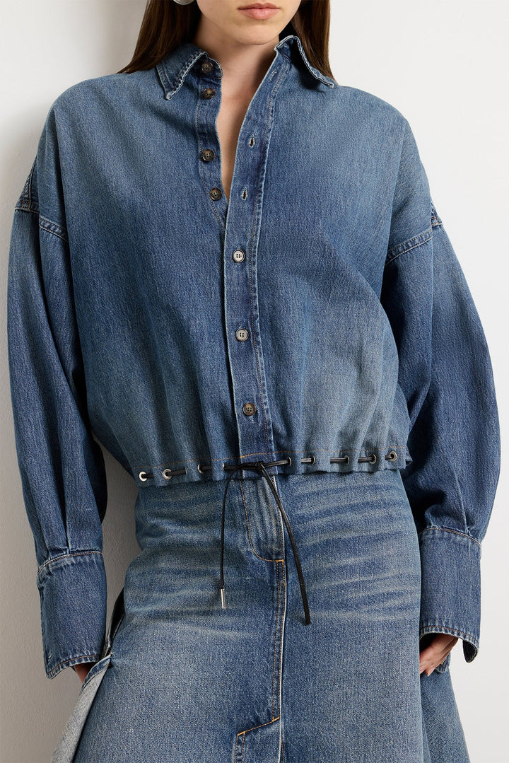 Person wearing a blue denim outfit on a plain background