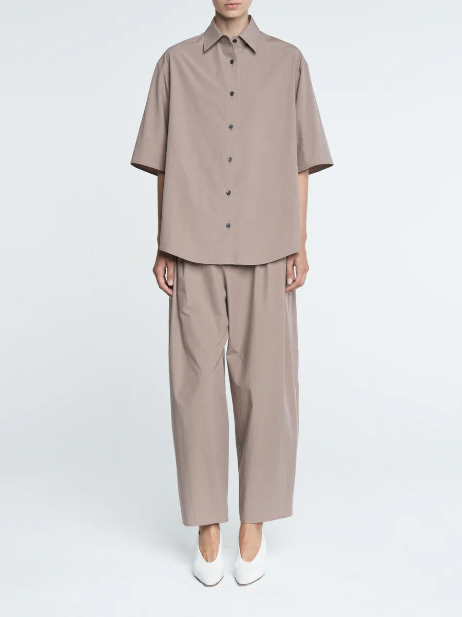 Person wearing a beige shirt and pants set on a white background