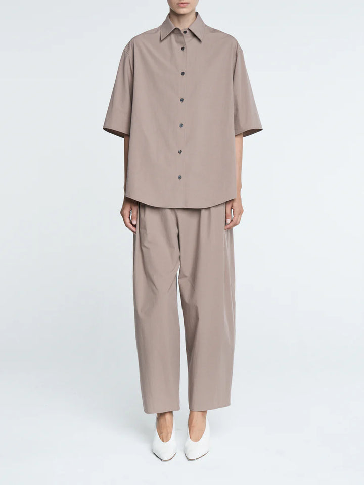 Person wearing a beige shirt and pants set on a white background