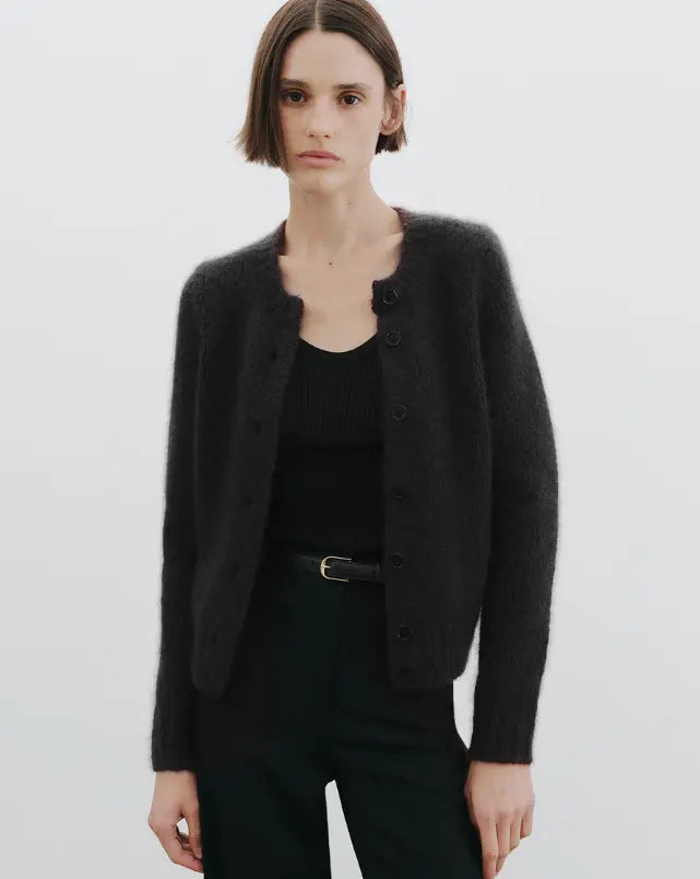 Person wearing a black cardigan over a black top on a white background