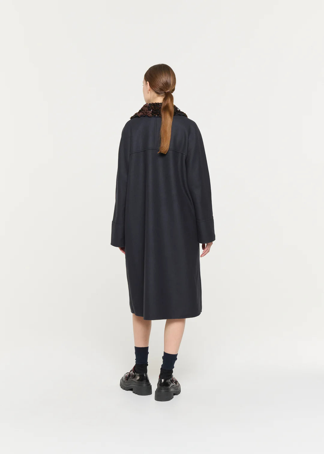 Person wearing a black coat on a white background