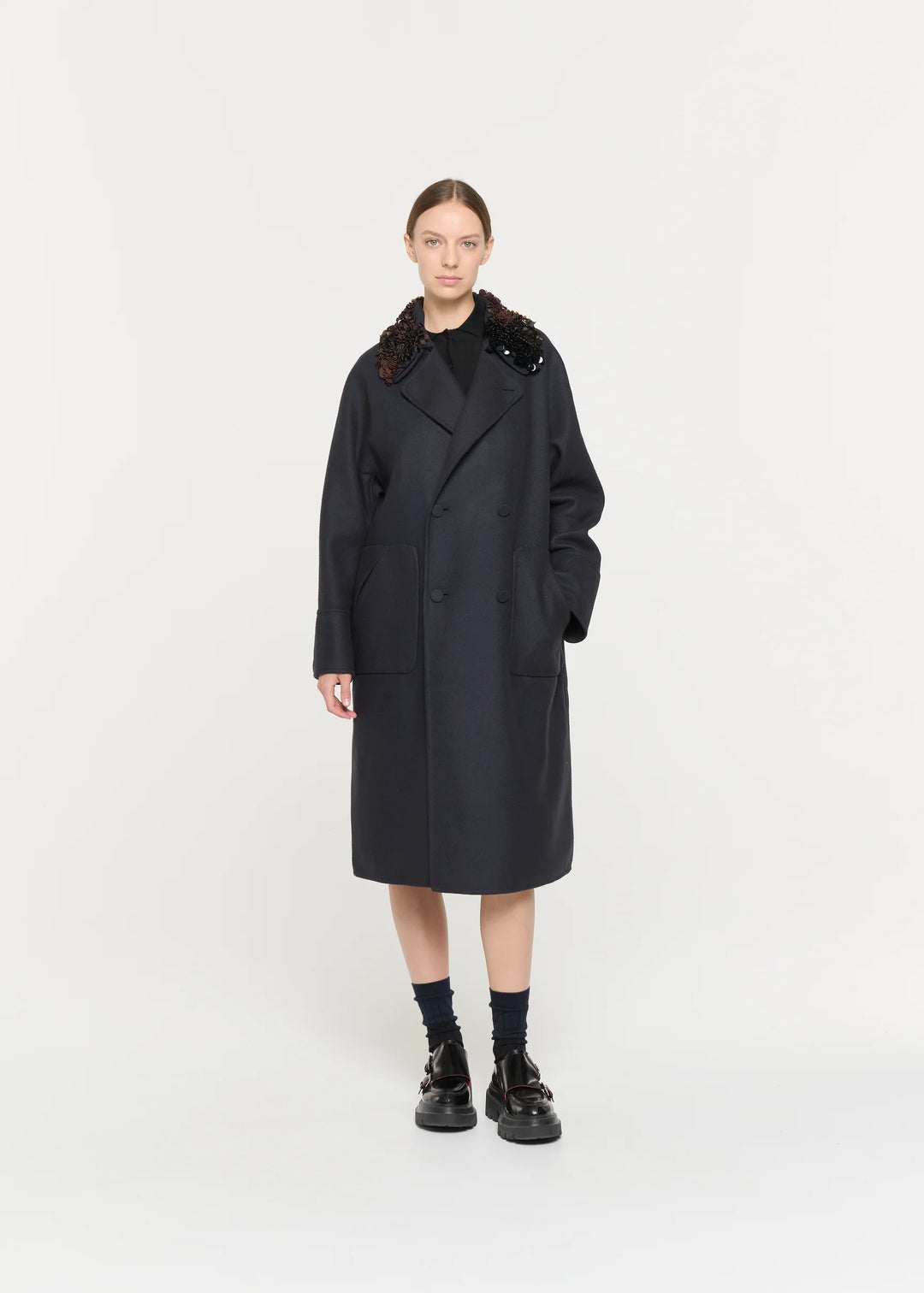 Person wearing a black coat with fur collar on a white background