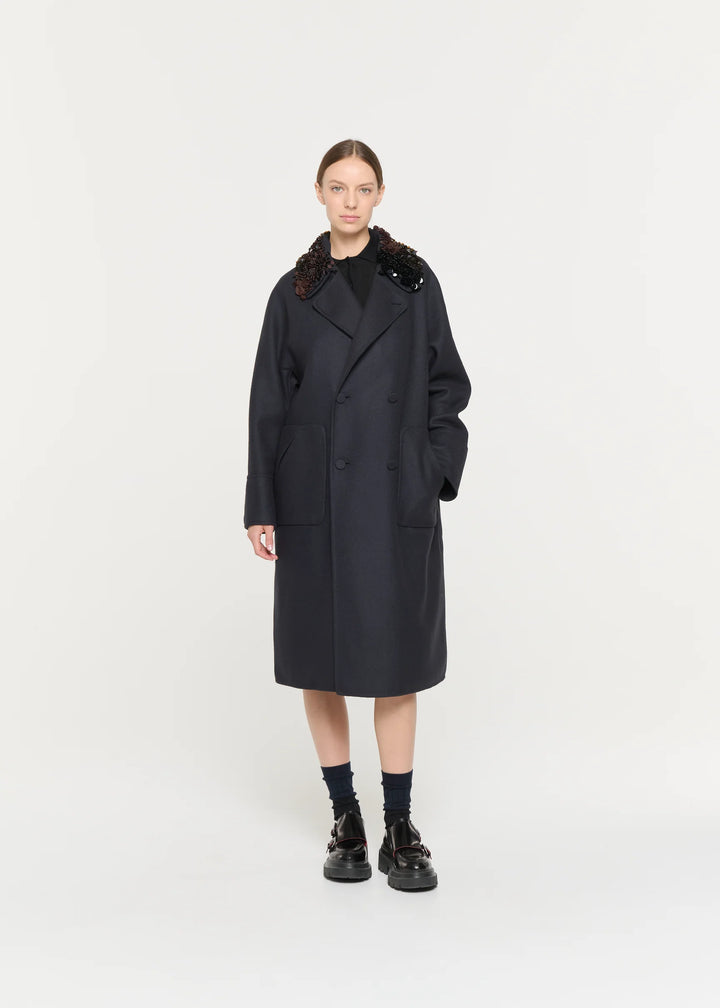 Person wearing a black coat with fur collar on a white background