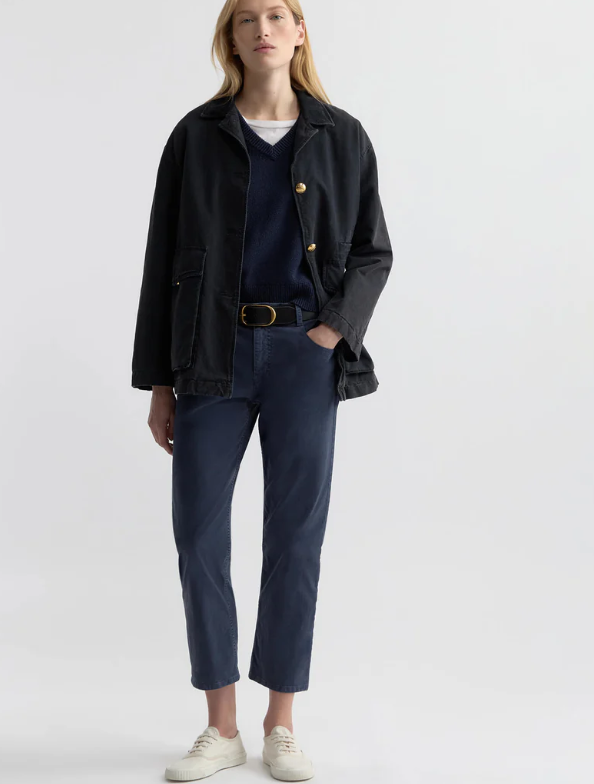 Person wearing a black jacket and navy pants on a white background