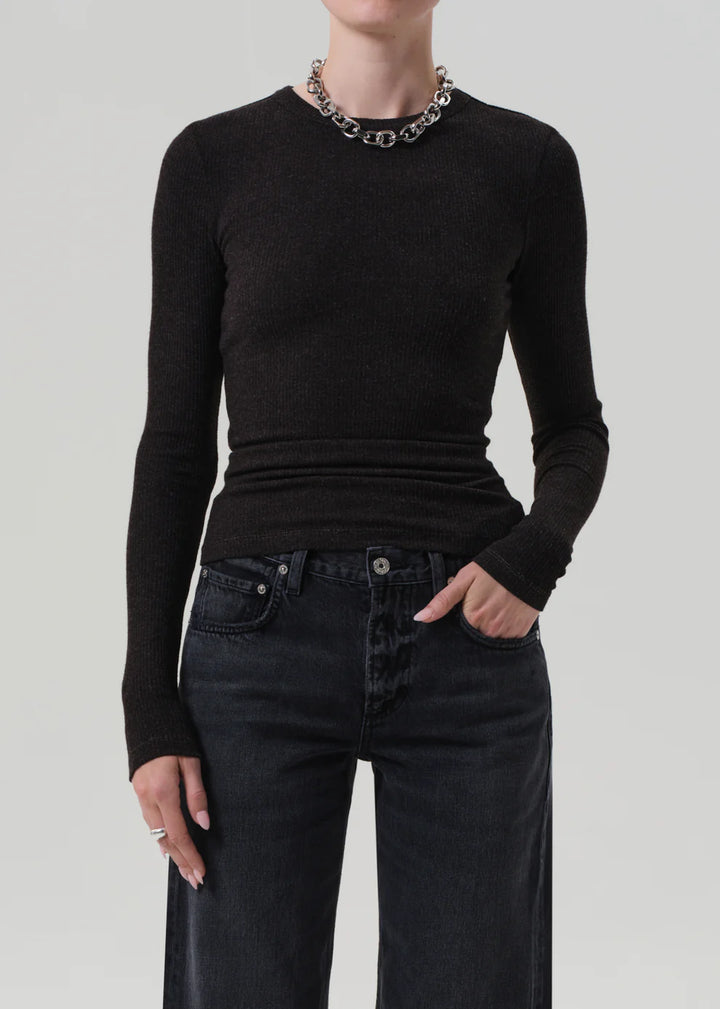 Person wearing a black long-sleeve top and black jeans on a light gray background