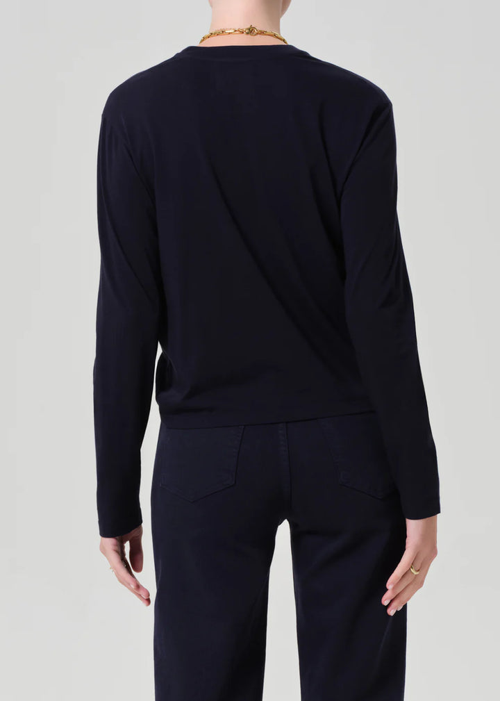 Person wearing a black long-sleeve top and pants on a light gray background