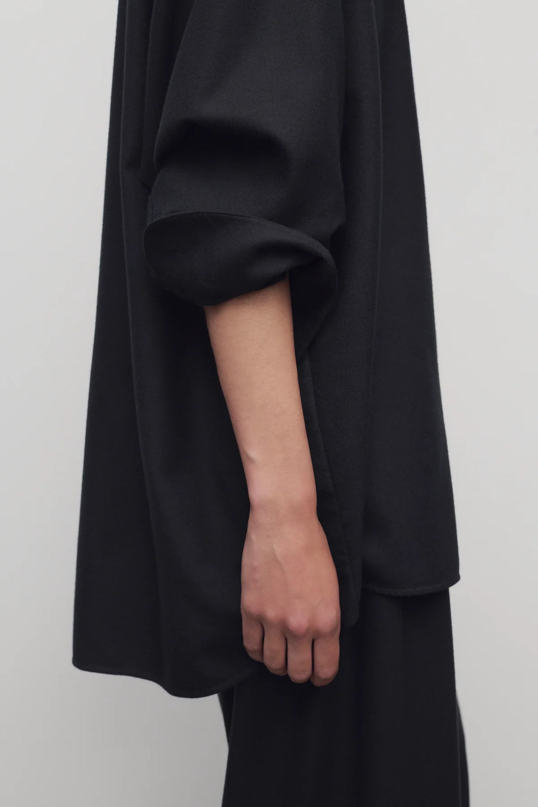 Person wearing a black outfit with a plain background