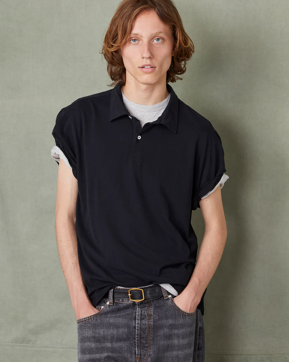 Person wearing a black polo shirt with white trim against a green background
