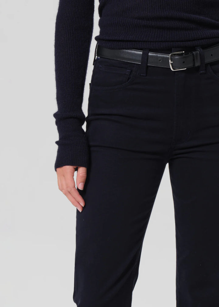 Person wearing a black ribbed sweater and black pants on a light gray background