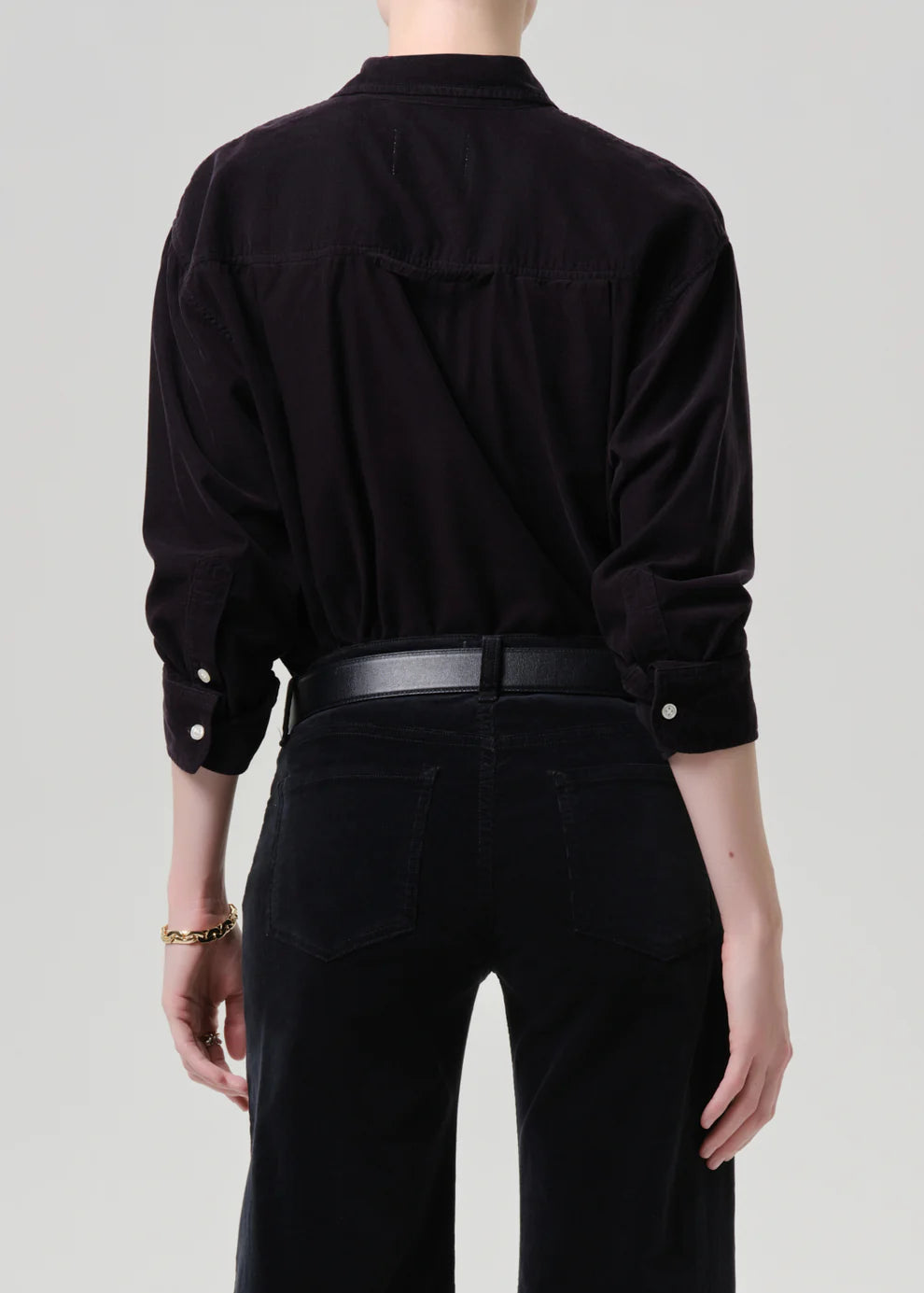 Person wearing a black shirt and black pants on a plain background