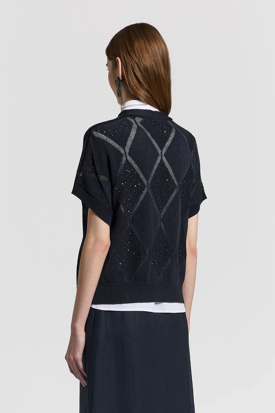 Person wearing a black short-sleeve cardigan with geometric pattern on a white background