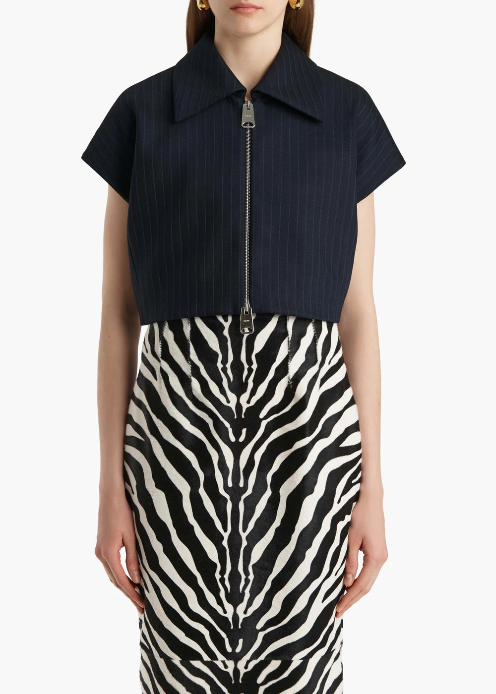 Person wearing a black short-sleeve top with a zipper and a zebra-patterned skirt on a white background