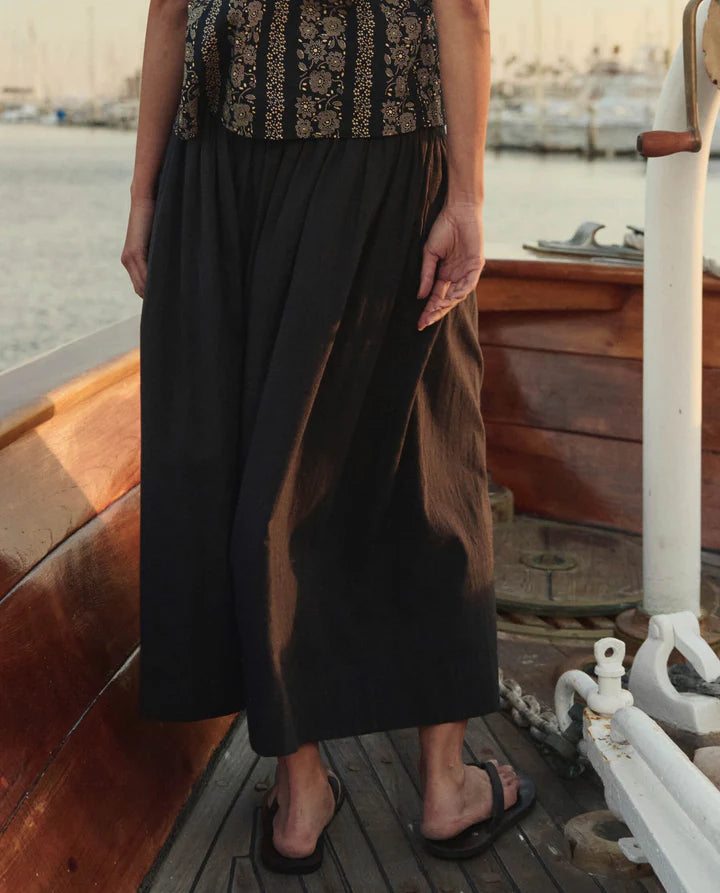 Person wearing a black skirt and patterned top on a boat deck.