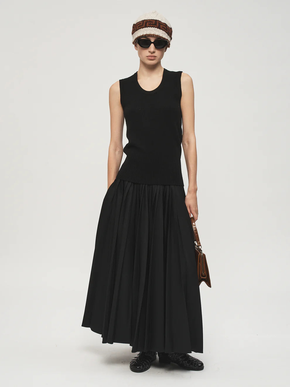 Person wearing a black sleeveless dress with a white background