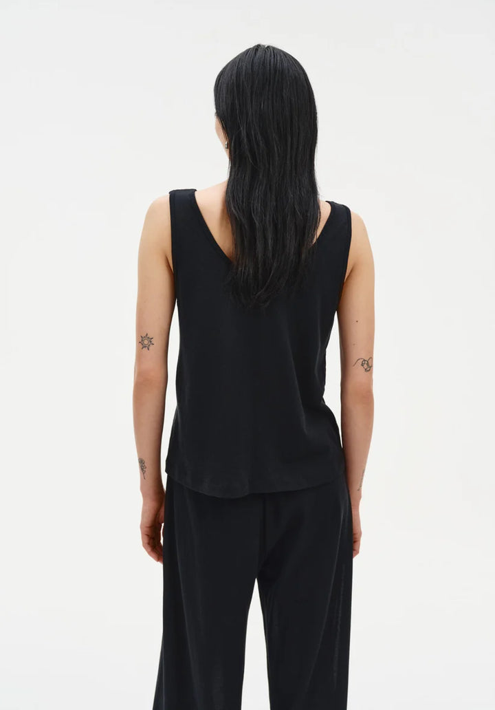 Person wearing a black sleeveless top and pants on a white background