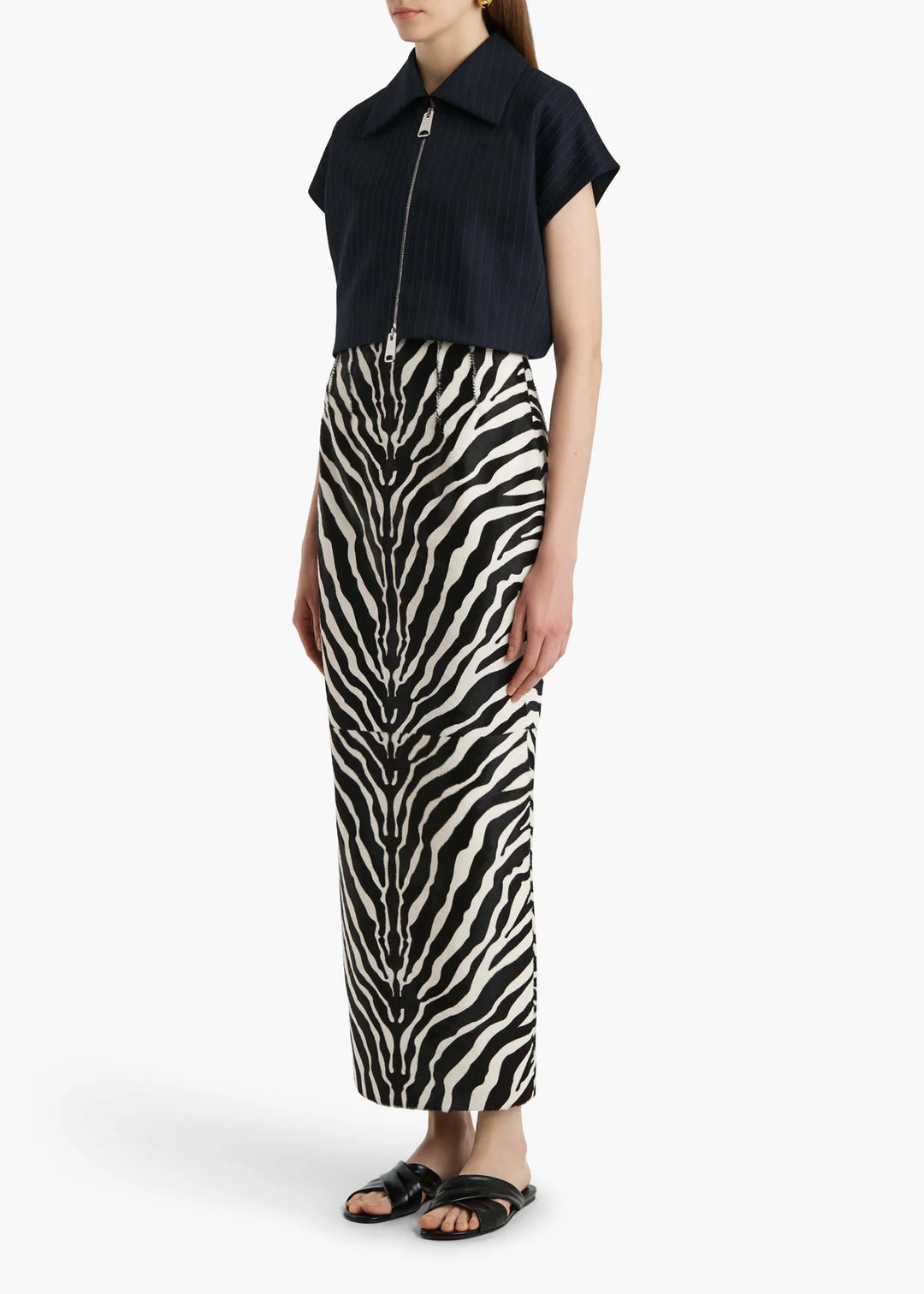 Person wearing a black sleeveless top and zebra print pants on a white background