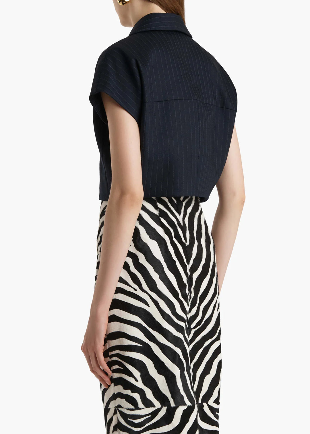 Person wearing a black sleeveless top and zebra print skirt on a white background