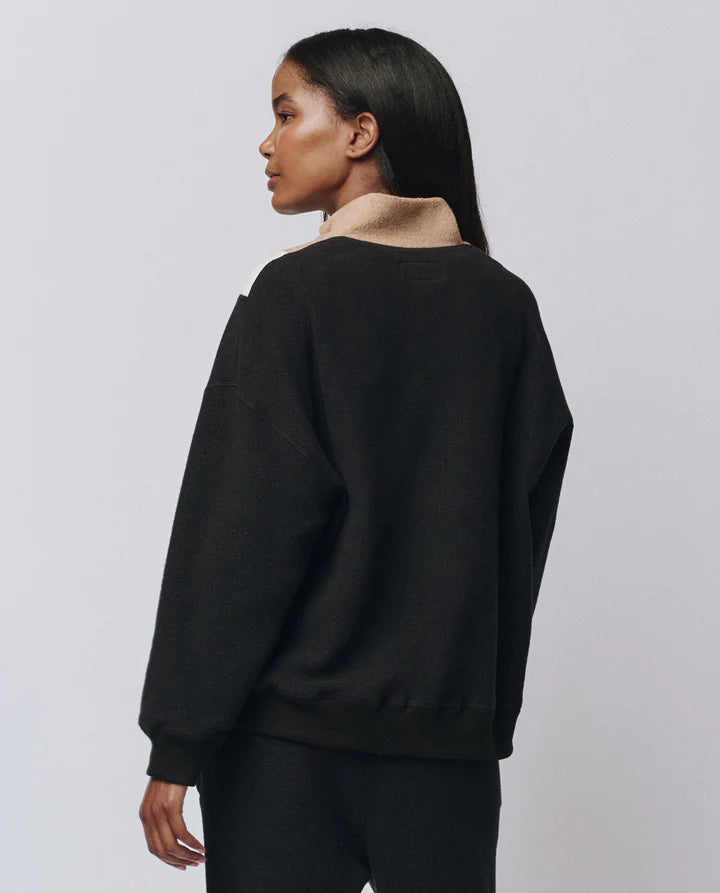 Person wearing a black sweater against a plain background