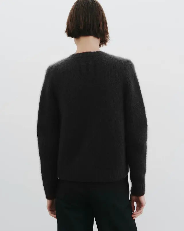 Person wearing a black sweater on a plain background