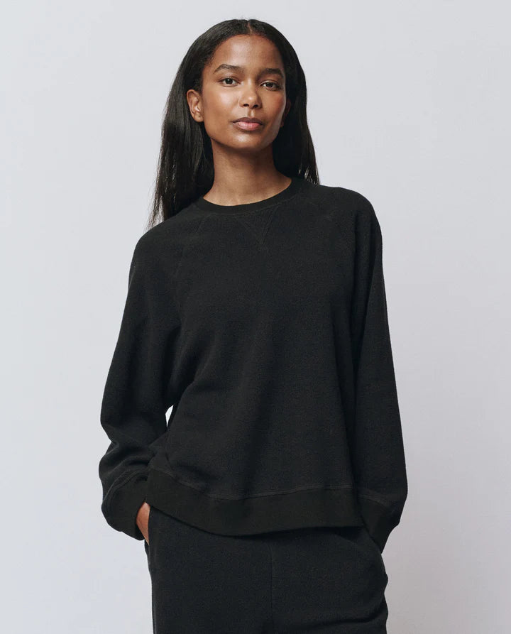 Person wearing a black sweatshirt against a plain background