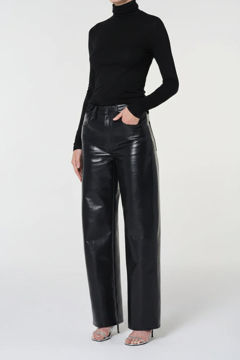 Person wearing a black turtleneck and black leather pants on a white background
