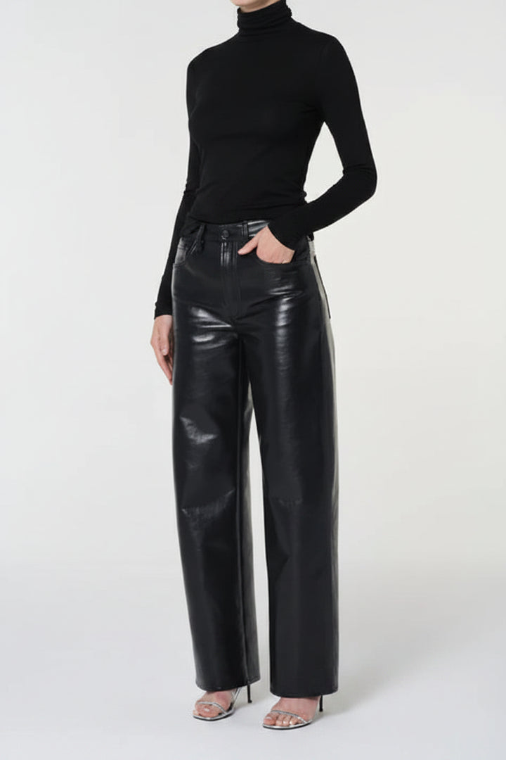 Person wearing a black turtleneck and black leather pants on a white background
