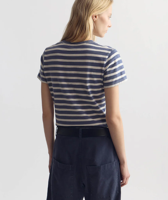 Person wearing a blue and white striped shirt with navy pants on a light gray background