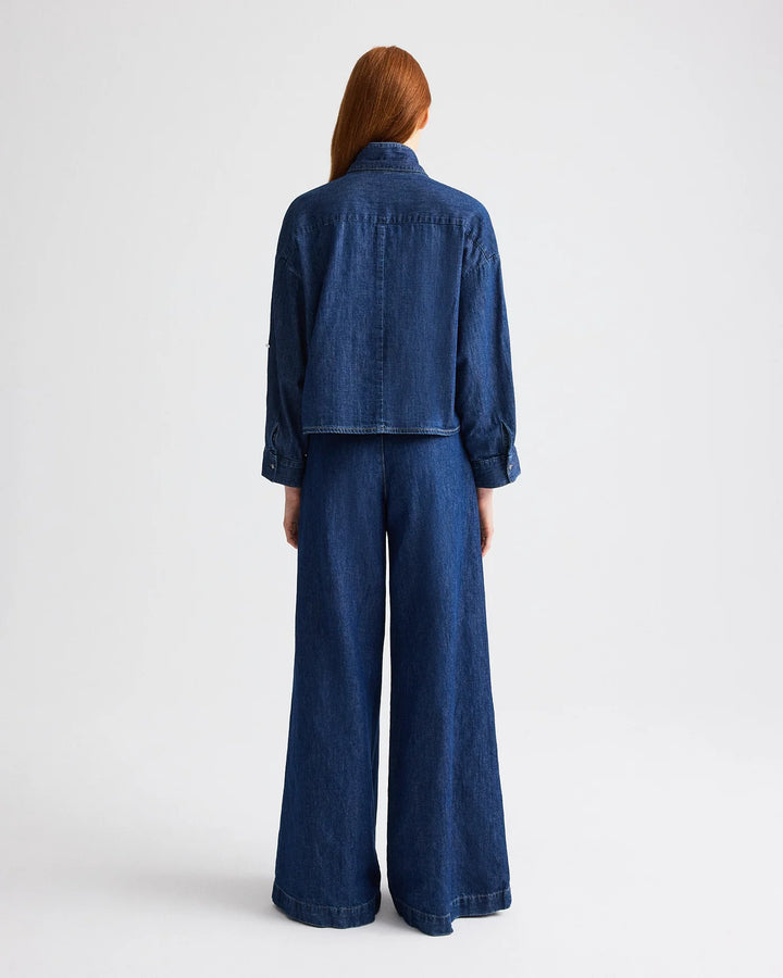 Person wearing a blue denim outfit on a white background