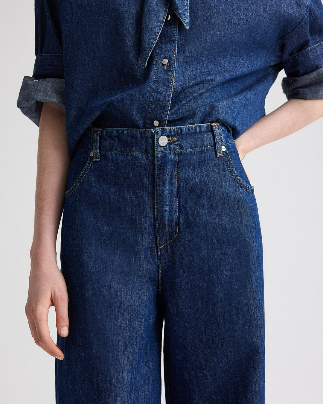 Person wearing a blue denim shirt and jeans on a white background