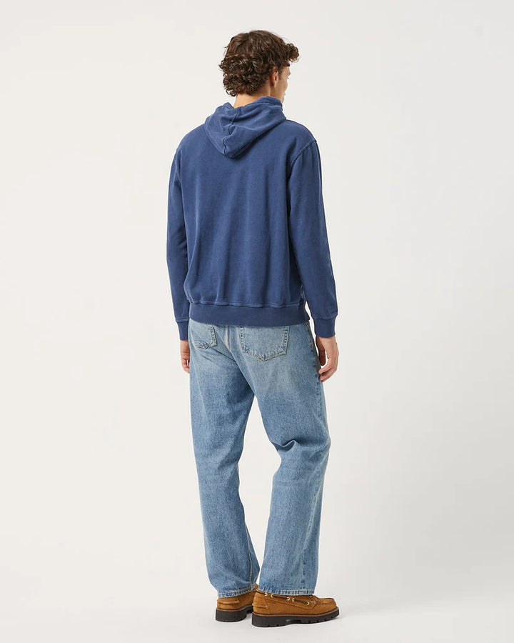 Person wearing a blue hoodie and jeans standing against a white background