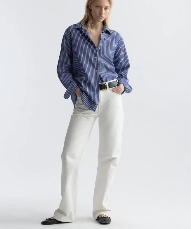 Person wearing a blue striped shirt and white pants on a white background