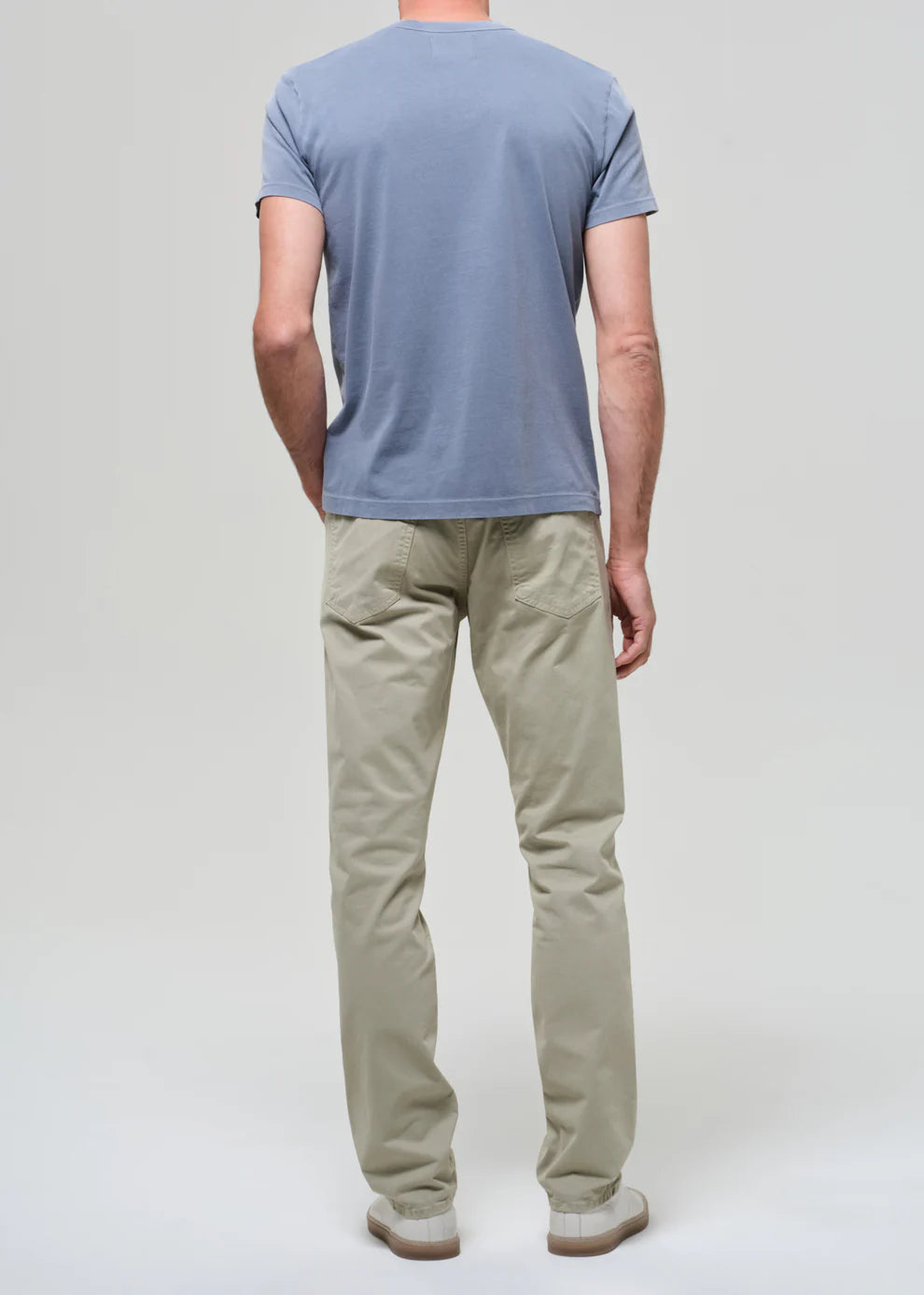 Person wearing a blue t-shirt and beige pants on a light gray background