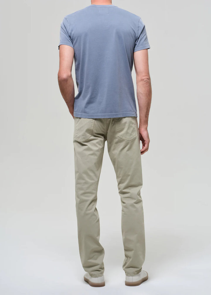 Person wearing a blue t-shirt and beige pants on a light gray background