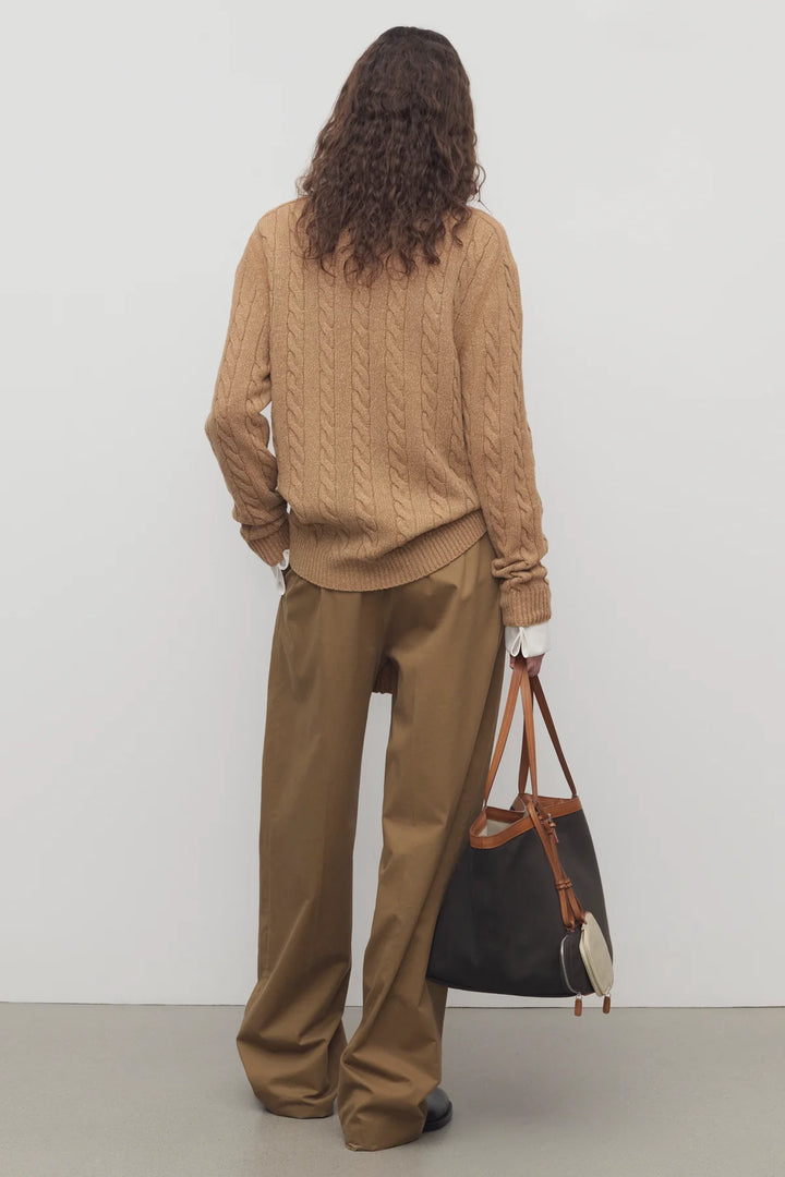 Person wearing a brown outfit with a handbag against a white background