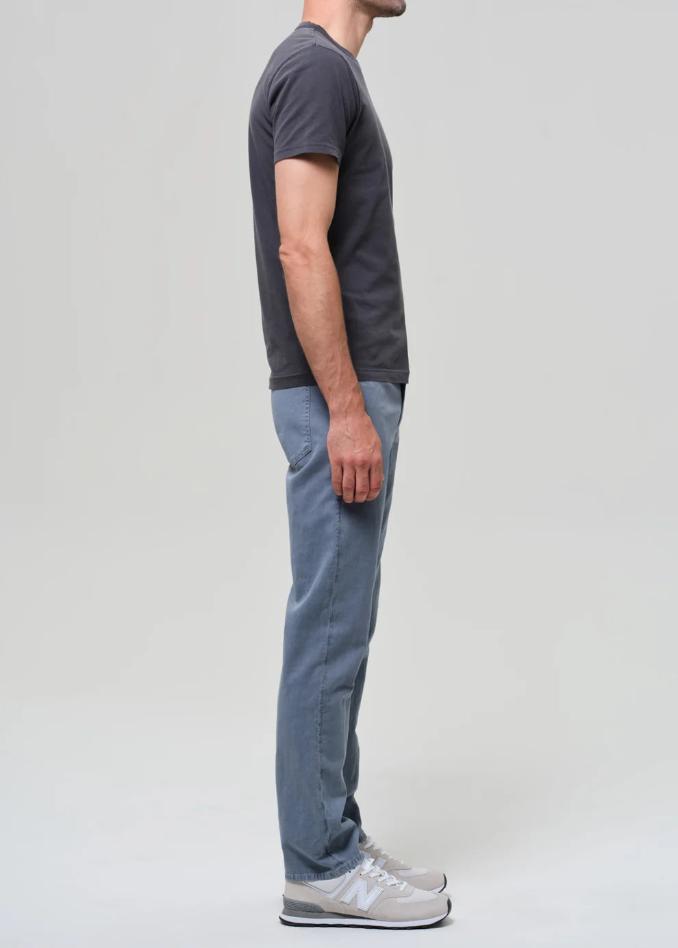 Person wearing a dark gray t-shirt and light blue jeans on a plain background