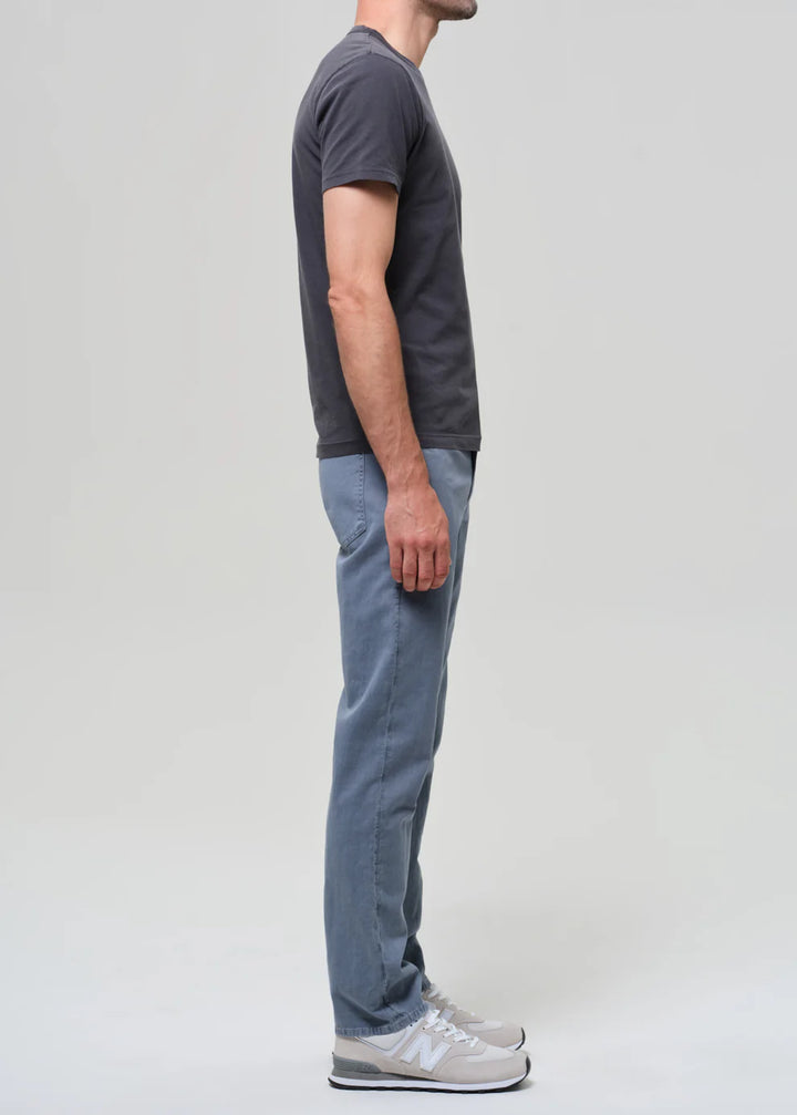 Person wearing a dark gray t-shirt and light blue jeans on a plain background
