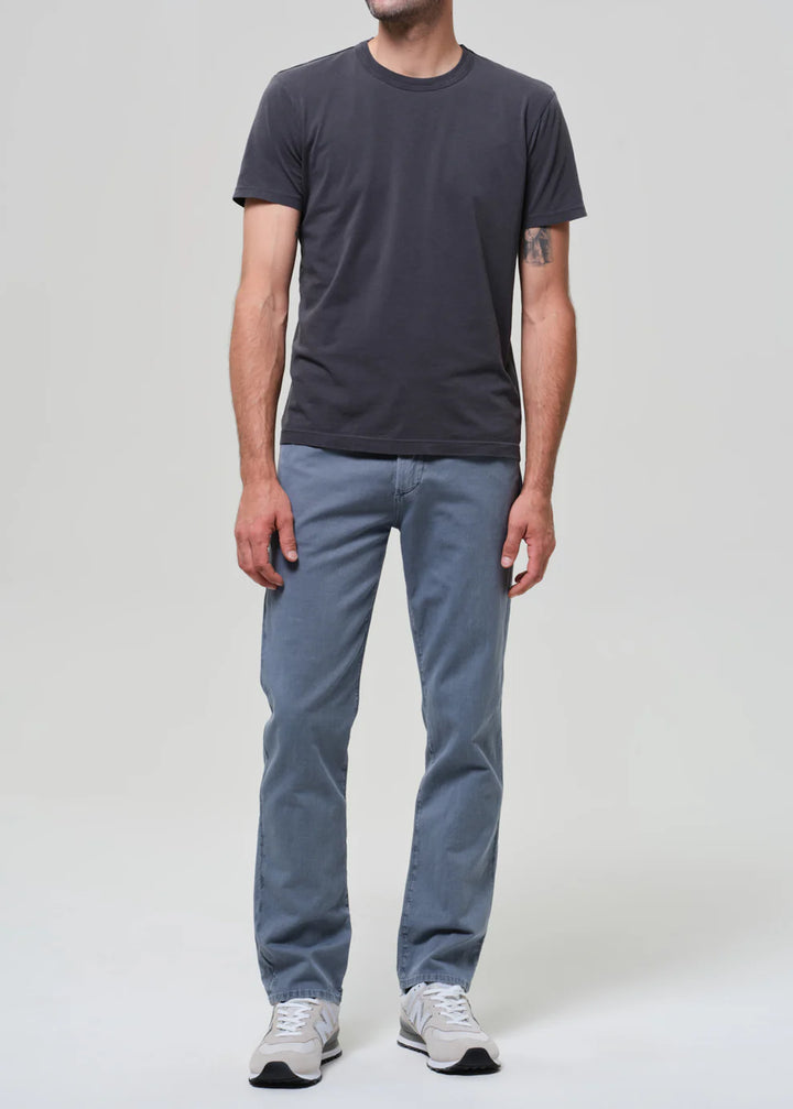Person wearing a dark gray t-shirt and light blue jeans on a white background