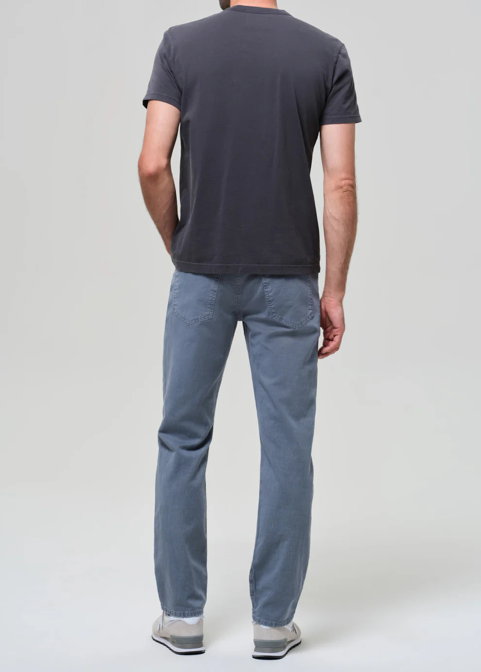 Person wearing a dark gray t-shirt and light blue pants on a white background