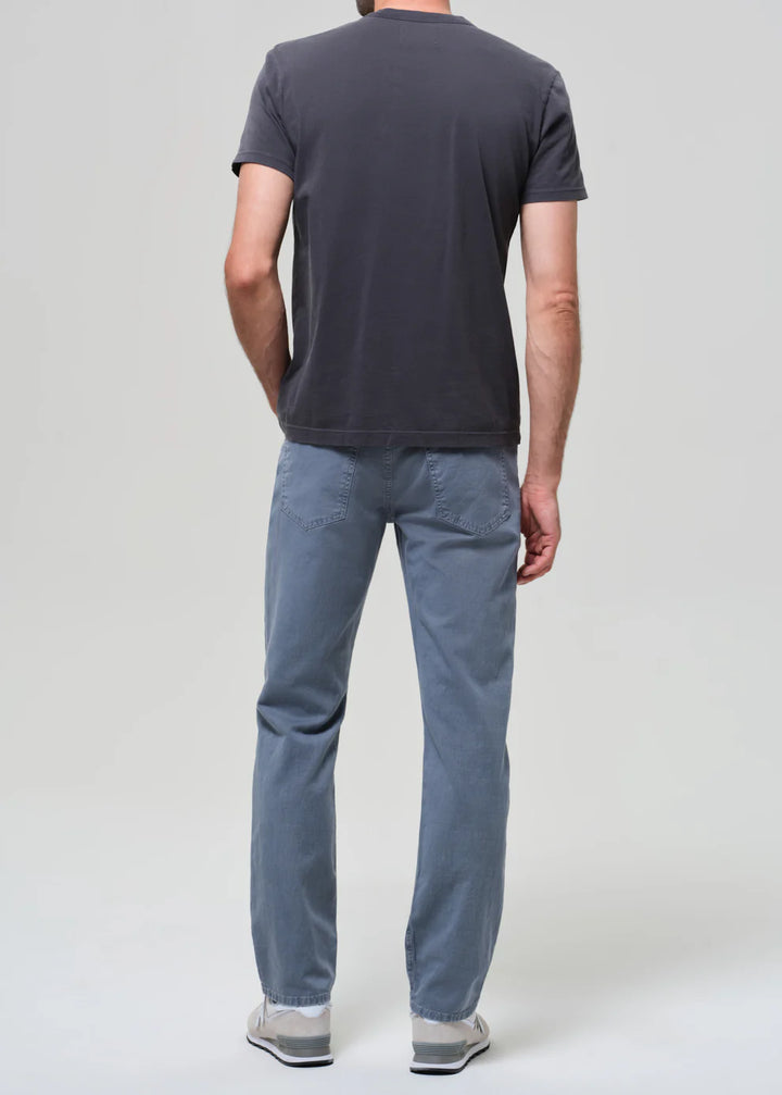 Person wearing a dark gray t-shirt and light blue pants on a white background